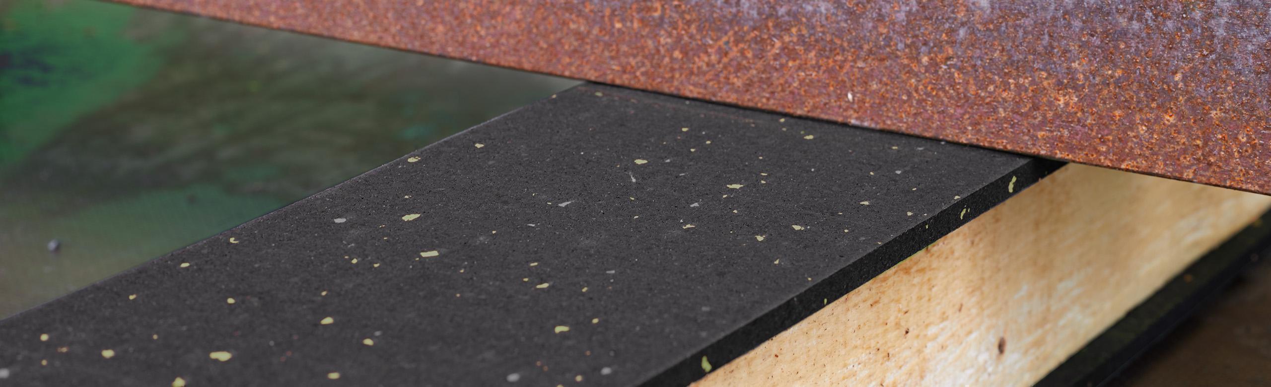 Black REGUPOL in use between a steel girder and a square timber Anti-slip mat for securing extremely heavy loads during use.